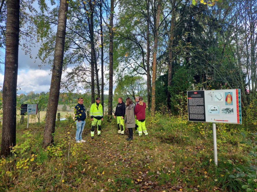 Ryhmä ihmisiä keskustelee arkeologisen kohteen maisemanhoidosta Rikalanmäen rautakautisessa kalmistossa